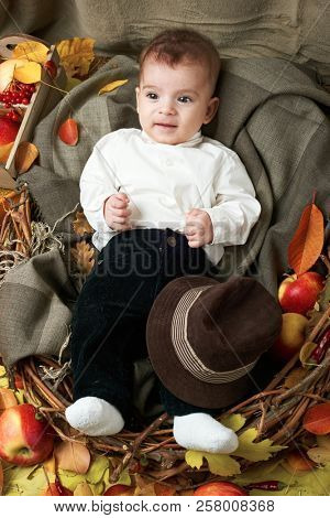 autumn concept - child boy lie on yellow leaves with fruits and vegatbles, red apples and pumpkins