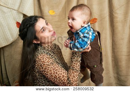 autumn concept - mother and child boy are on yellow leaves with fruits and vegatbles, red apples and pumpkins