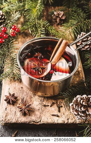 Hot Mulled Wine Drink With Lemon, Apple, Cinnamon, Anise And Other Spices In Casserole Between Fir T