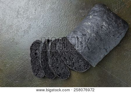 Sliced Black Bread Colored With Squid Ink On Dark Background, Top View