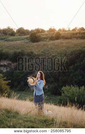 Girl In A Hat Playing With A Dog In The Field At Sunset Sun
