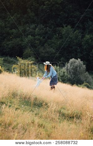 Girl In A Hat Playing With A Dog In The Field At Sunset Sun