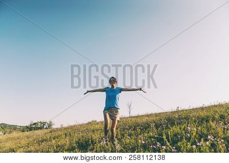 A Girl Is Walking Along The Field. A Woman Walks Through The Meadow, Arms Outstretched. Wildflowers 