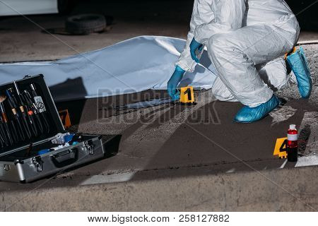 Cropped Image Of Criminologist In Protective Suit And Latex Gloves Collecting Evidence At Crime Scen