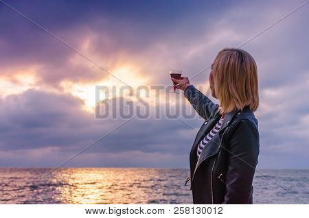 Girl Holding A Glass With Wine Uring The Sunset On The Sea