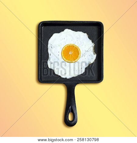 Square Cast-iron Frying Pan With Fried Eggs, Slice Of Orange Instead Of Yolk. Artificial Objects Tha
