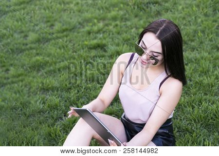 Waist-up Portrait Of Charming Young Female Working On Portative Computer And Laying On Fresh Green G