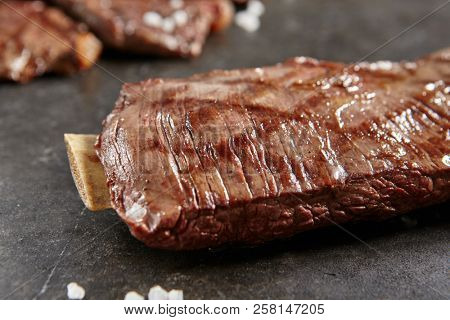 Hot Grilled Whole Flank Steak on Black Stone Background. Fresh Juicy Medium Rare Beef Grillsteak. Barbecue Meat Close Up
