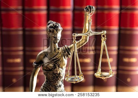 Gold Colored Justice Statue In Front Of Red Law Books
