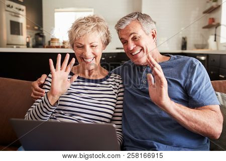 Senior couple video calling on a laptop waving at screen