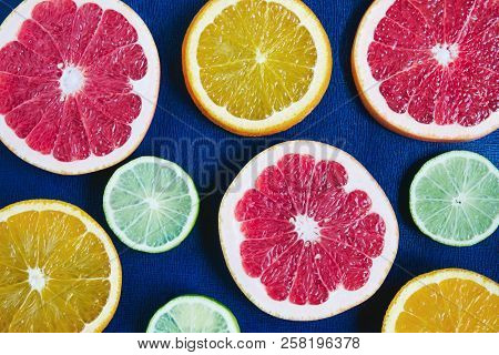 Blue Background With Citrus Slices: Orange, Grapefruit, Lemon, Lime. Contrast Of Colors