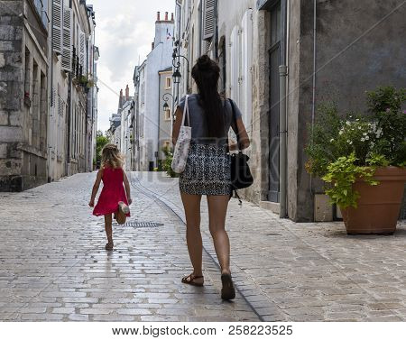 Orleans, France - August 11, 2018: Small Alley With Trunning Child And Walking Woman And With Old Hi