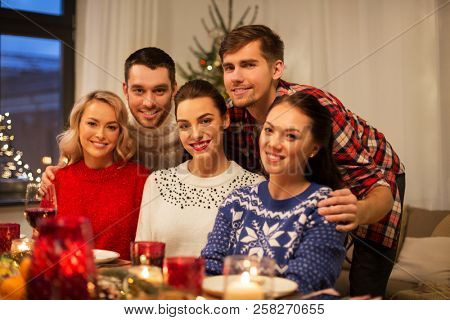 holidays and celebration concept - happy friends having christmas dinner at home