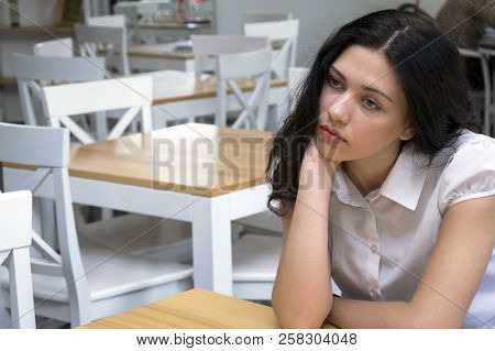 Portrait Of Good-looking Pensive Brunette Sitting At Work And Dreaming Looking Faraway. Cute Young W