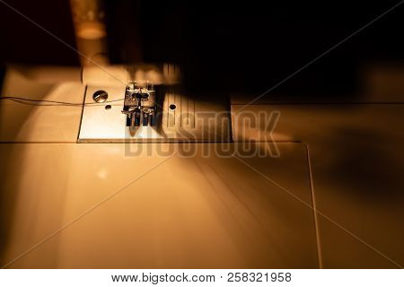 Modern Compact Electric Sewing Machine In The Evening. View Of Needle And Thread. Illumination From 