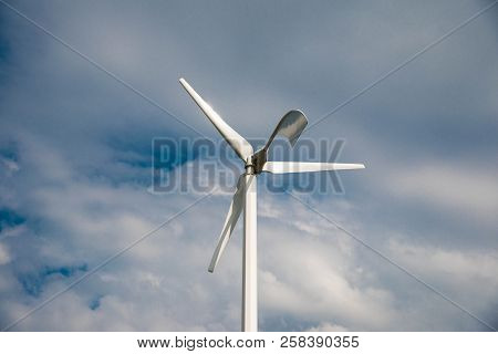 White Small Eolian Wind Turbine Close Up, Blue Sky With White Clouds In The Background.