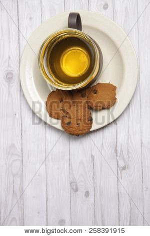 A Cup Of Green Tea With Choco Chips Cookies On White Wooden Table