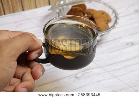 Handling A Cup Of Green Tea To Drink With Cochco Chips Cookies For Background