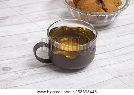 A Cup Of Green Tea With Choco Chips Cookies On White Wooden Table