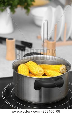Stewpot With Water And Corn Cobs On Stove In Kitchen