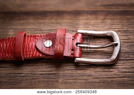 Leather Belt On A Wooden Background. Girdle Of Red Leather.