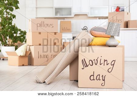 Moving Boxes And Household Stuff In Kitchen. Space For Text