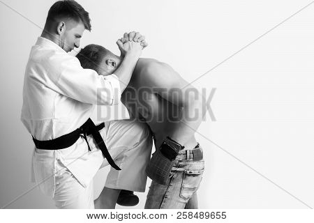 Karate Athlete In Kimono With Black Belt Kicking Knee At Boxer With Naked, Muscle Torso In Red, Boxi