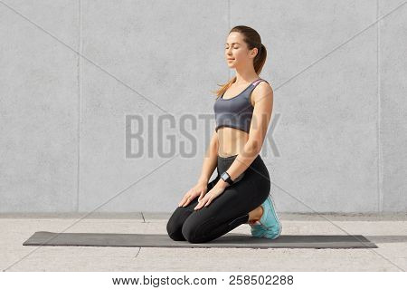 Concentrated Young Sporty European Fitness Woman Sits On Mat, Tries To Take Break After Stretching O
