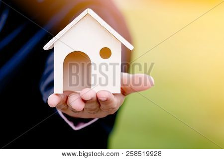 Businessman Hand Holding A Model Home In The Public Park, Saving Money For Buy A New House Or Loan F