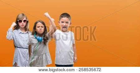 Group of boy and girls kids over orange background annoyed and frustrated shouting with anger, crazy and yelling with raised hand, anger concept