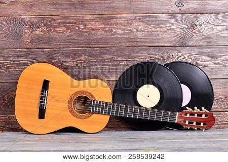 Acoustic Guitar And Vinyl Records. Musical Instuments On Wooden Background. Vintage Musical Backgrou