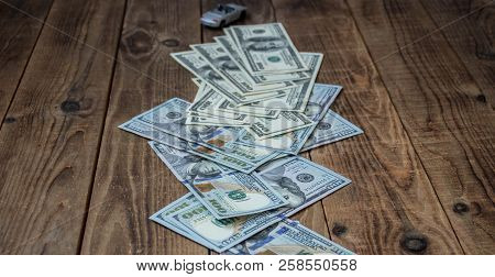 A Stack Of One Hundred Dollar Bils On Wooden Background