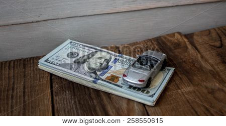 A Stack Of One Hundred Dollar Bils On Wooden Background
