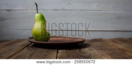 A Bite Pear On A Plate On Wooden Background