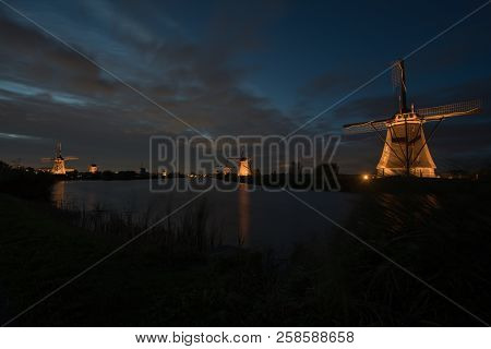 These Beautiful Windmills In Kinderdijk Are Illuminated With White Light At The Blue Hour