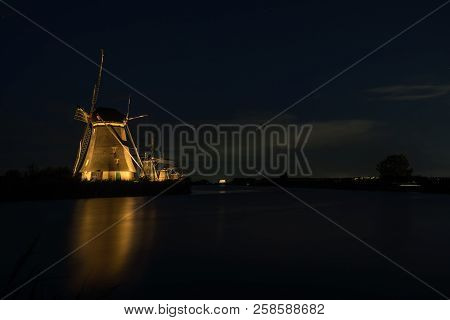 These Beautiful Windmills In Kinderdijk Are Illuminated With White Light At The Blue Hour
