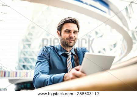 A Young Businessman With Tablet Leaning On A Railing In A Modern Building.