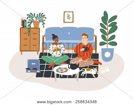 Young Romantic Couple Sitting On Floor, Drinking Tea And Eating Cookies In Evening. Man And Woman Sp