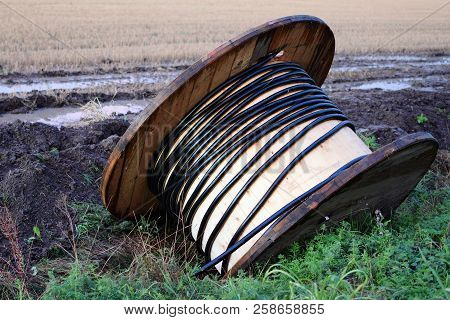 Almost Empty Wooden Cable Reel In Clayey Ground After Rain.