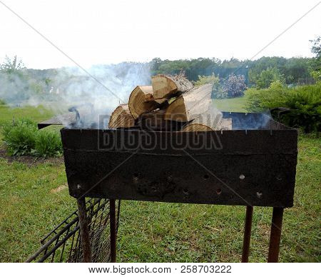 Beautiful Red Fire From Slice Wood, Dark Grey Black Coals Inside Metal Brazier. Wood Burning In The 