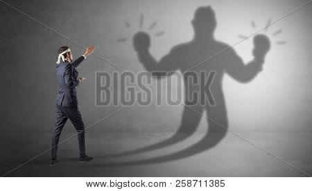 Businessman trying to fight with his unarmed shadow