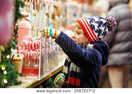 Little Cute Kid Boy Buying Sweets From A Cancy Stand On Christmas Market
