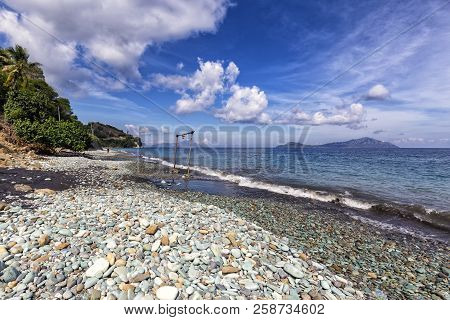 Waves Crash Near A Swing At Blue Stone Beach In Flores, Indonesia.