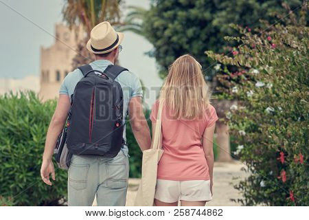 Travelling European Couple In Love Walking Together By Footway. Back View.