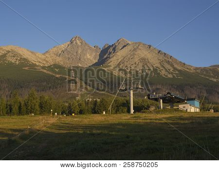 Tatra Mountains Range Gold Colored Sunrise Light , Ski Lift At Tatranska Lomnice With Green Trees An
