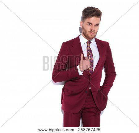 smiling young sexy businessman holding collar and one hand in pocket on white background