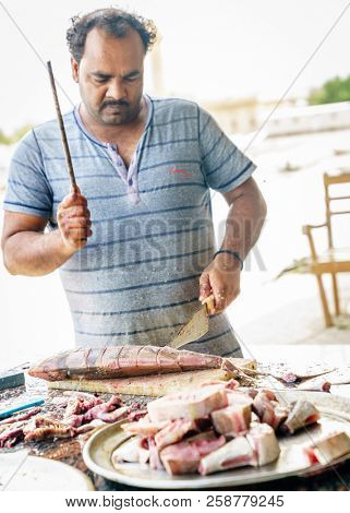 Dibba, Al Fujairah, UAE, November 25, 2016: a local fisherman cleaning fish near Dibba Port, UAE