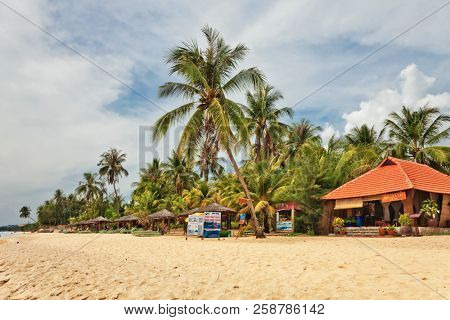 PHU QUOC, VIETNAM - APRIL 18, 2014:Tourists relaxing at beautiful tropical beach with  palms near small resort at Phu Quoc island  in Vietnam.