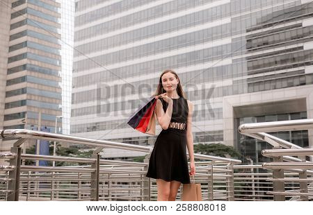 Portrait Of Beautiful Female In Black Dress Smling And Holding Shopping Bags In City,lifestyle Conce