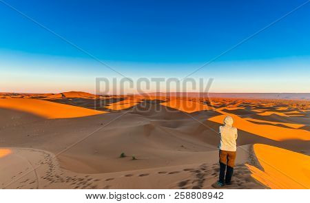 Woman Enjoing Sunrise In The Sahara Desert Next To M'hamid In Morocco